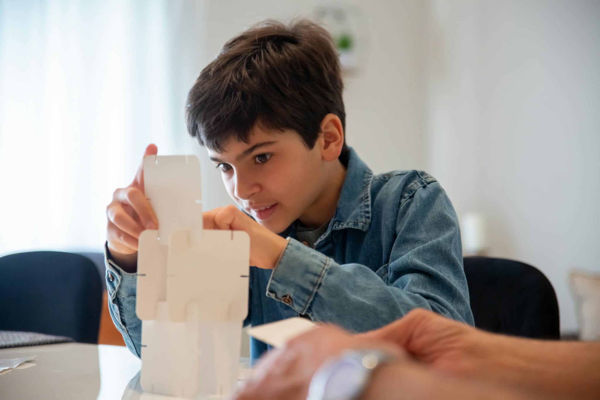 Young boy concentrating on assembling a puzzle at home, showcasing creativity and problem-solving skills.