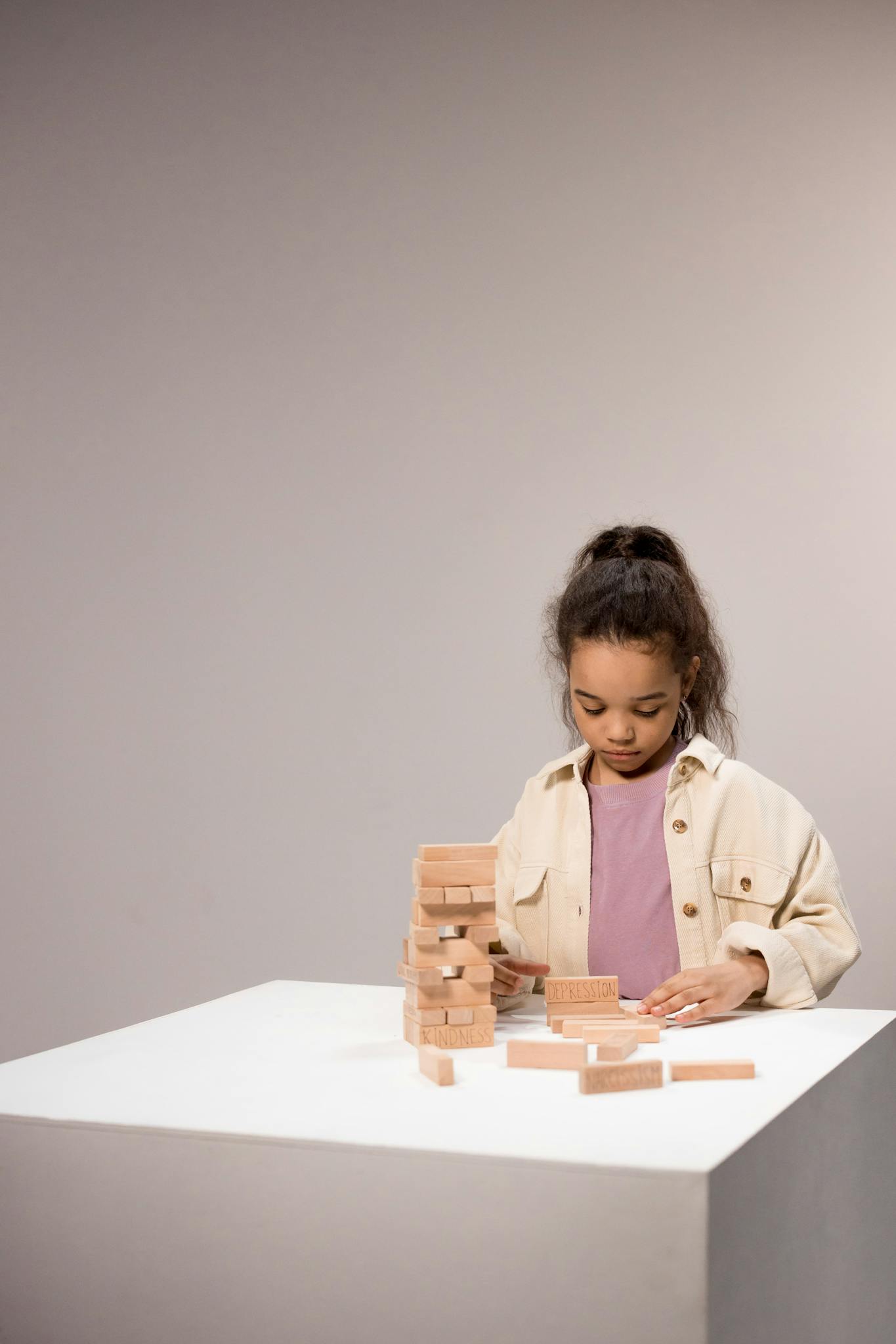 Young girl playing with a tower of wooden blocks, focused and concentrated indoors.